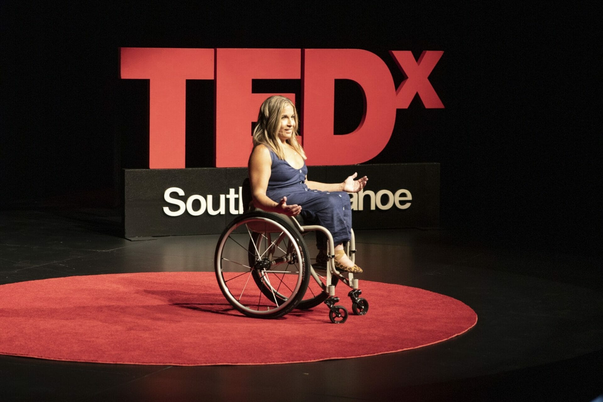 alycia speaking on the tedx south lake tahoe red dot with the tedx logo behind her