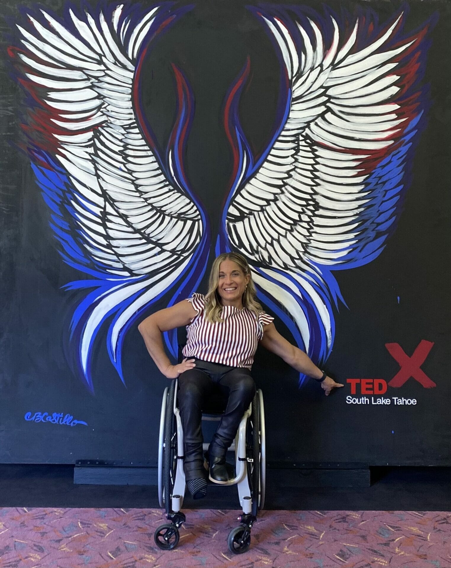 alycia in front of a wings painting in south lake tahoe pointing at tedx logo