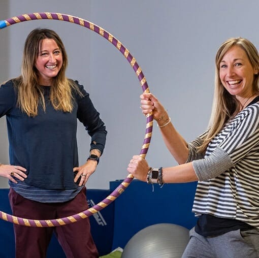 carli ross and coworker holding hoola hoop and smiling