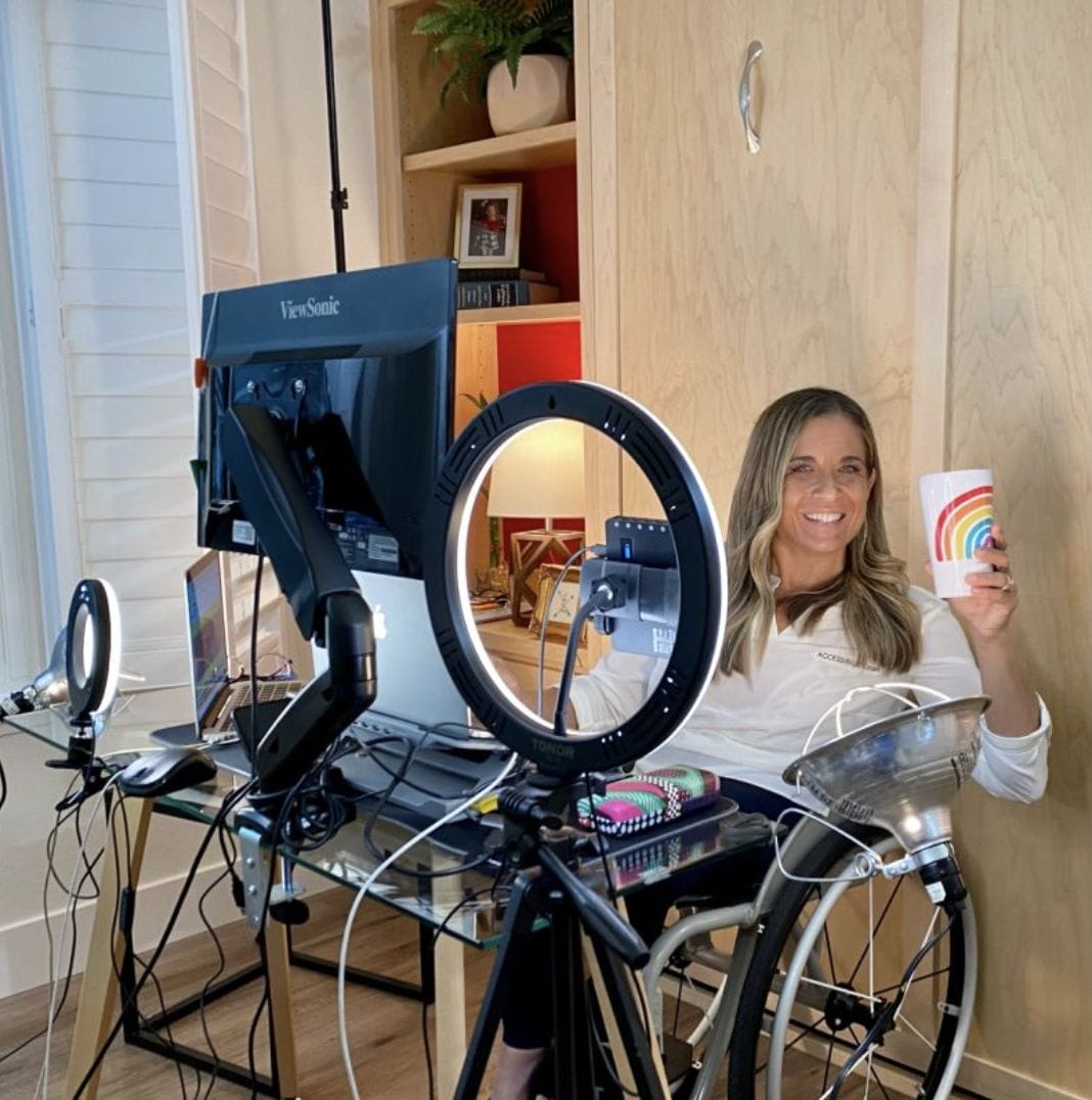 alycia behind her desk holding a rainbow cup and smiling