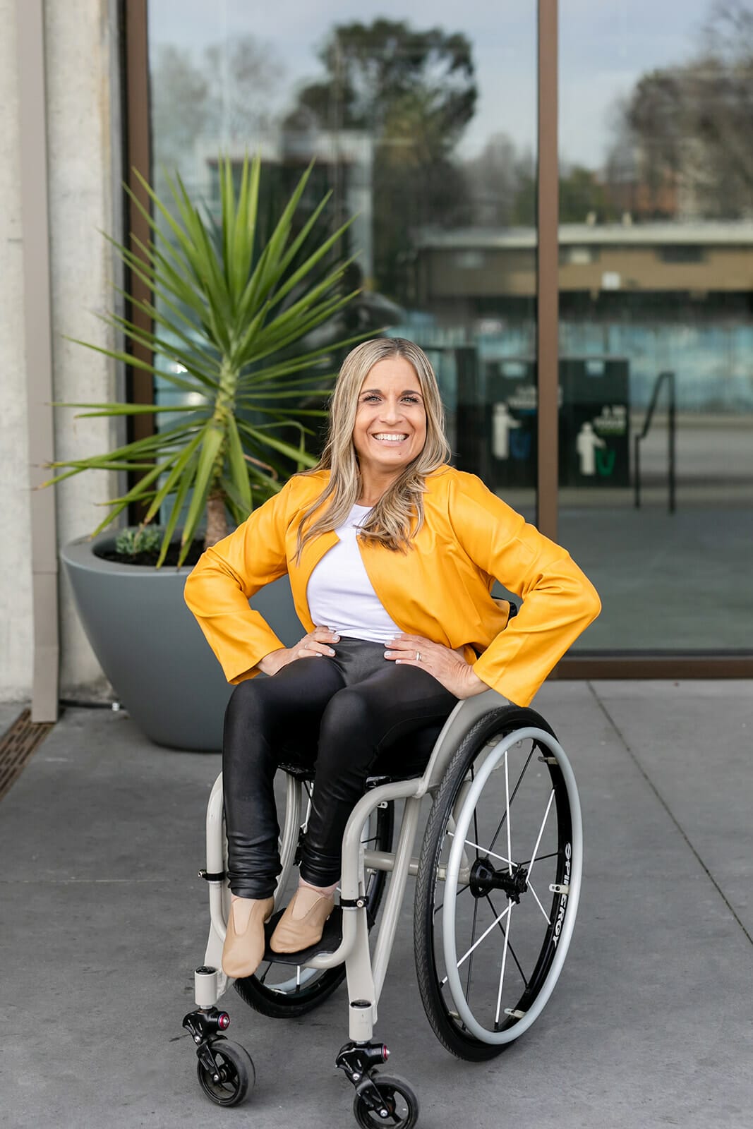 alycia smiling with hands on hips in yellow jacket