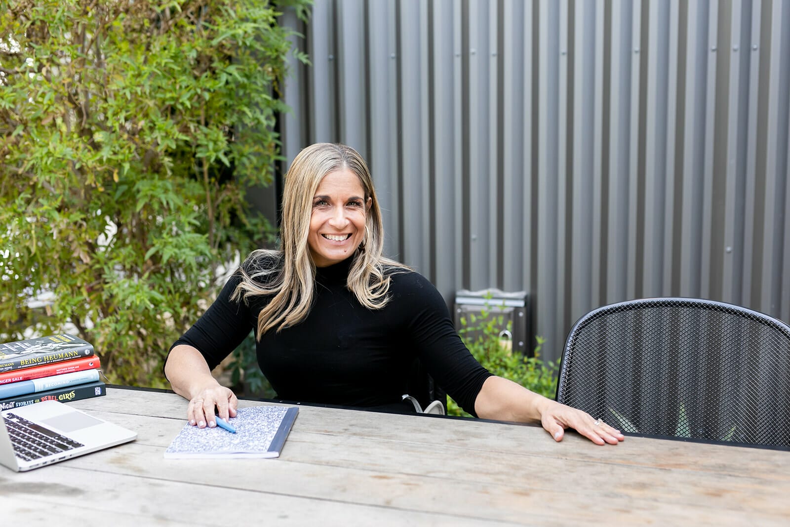 alycia sitting at table with her hand inviting you to an empty seat