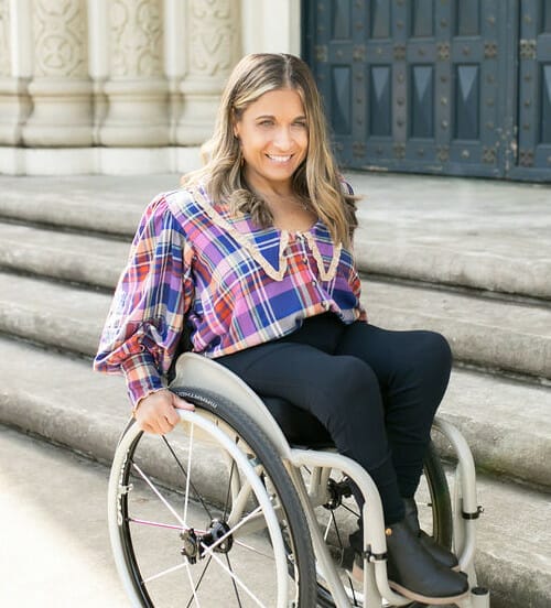 alycia sitting in her wheelchair by stairs leading up to a door