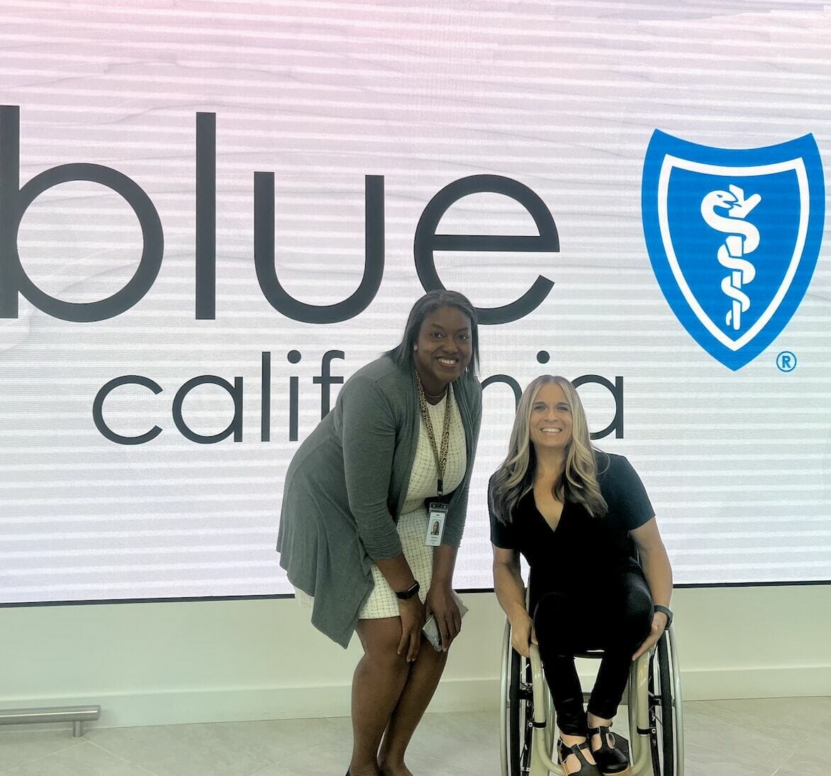 saffy and alycia in front of digital wall displaying blue shield logo