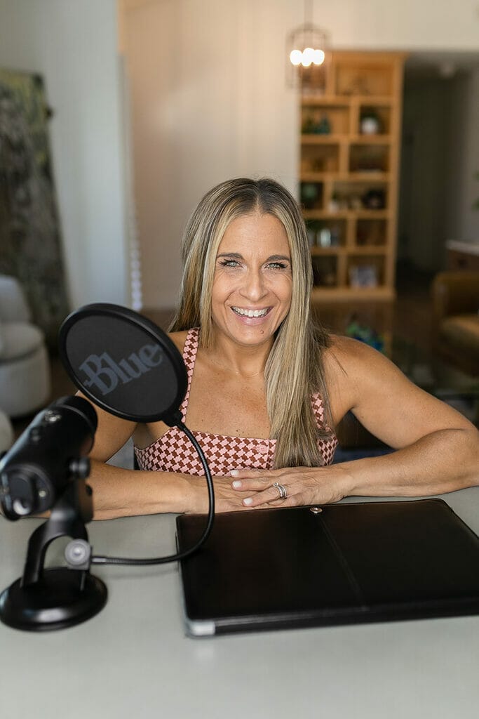 Alycia sitting at deck with podcast microphone giving an interview