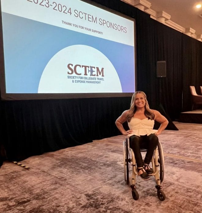 Alycia in front of SCTEM logo getting ready to go on stage for keynote.