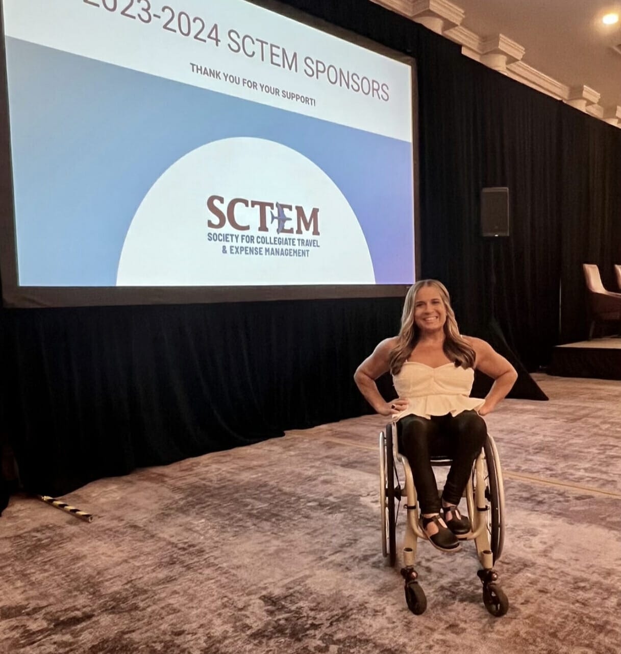 Alycia in front of SCTEM logo getting ready to go on stage for keynote.