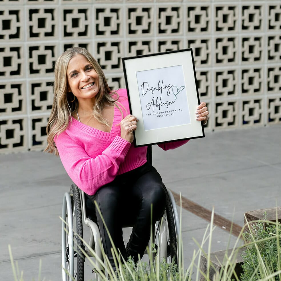 alycia sitting in her wheelchair holding a frame that says disabling ableism the modern pathway to inclusion