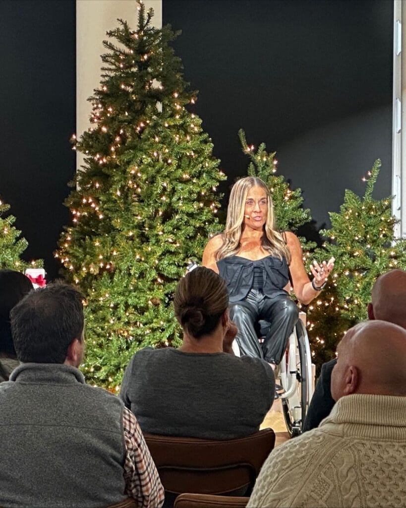 alycia speaking on victorias secret stage in front of christmas tree with hands open
