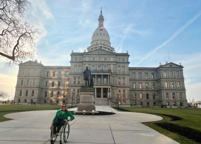 alycia sitting in front of the michigan state capital building in her wheelchair