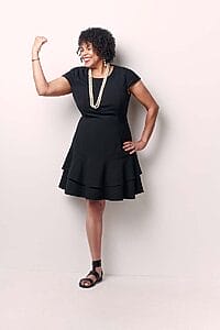 doctor donna walton standing in a dress flexing one arm with the other arm on her hip
