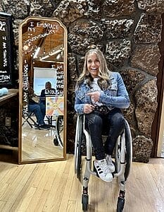 alycia sitting in her wheelchair next to a mirror that has positive slogans written on it to inspire the attendees of the nami youth symposium