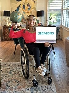 alycia sitting in her wheelchair holding a globe and her laptop with the siemens logo on the screen