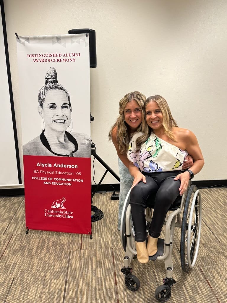 alycia and regina next to a banner of alycia