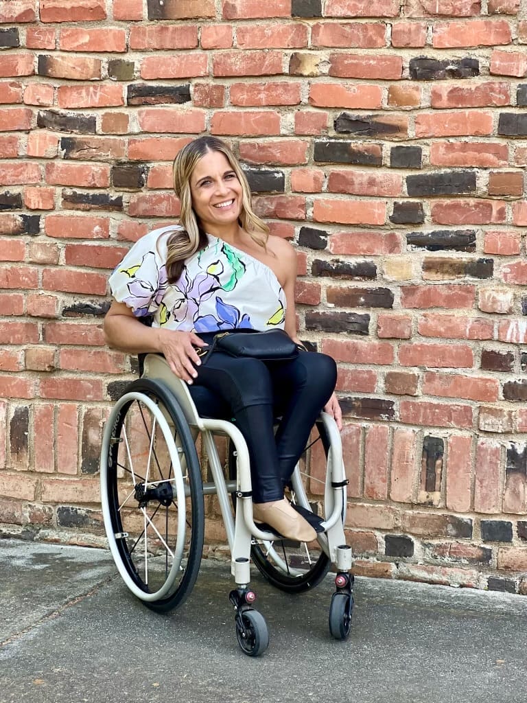 alycia sitting in her wheelchair in front of a brick wall on campus at chico state