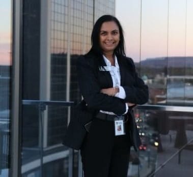 joanne lopez standing in front of a mirrored wall reflecting large buildings and a cityscape