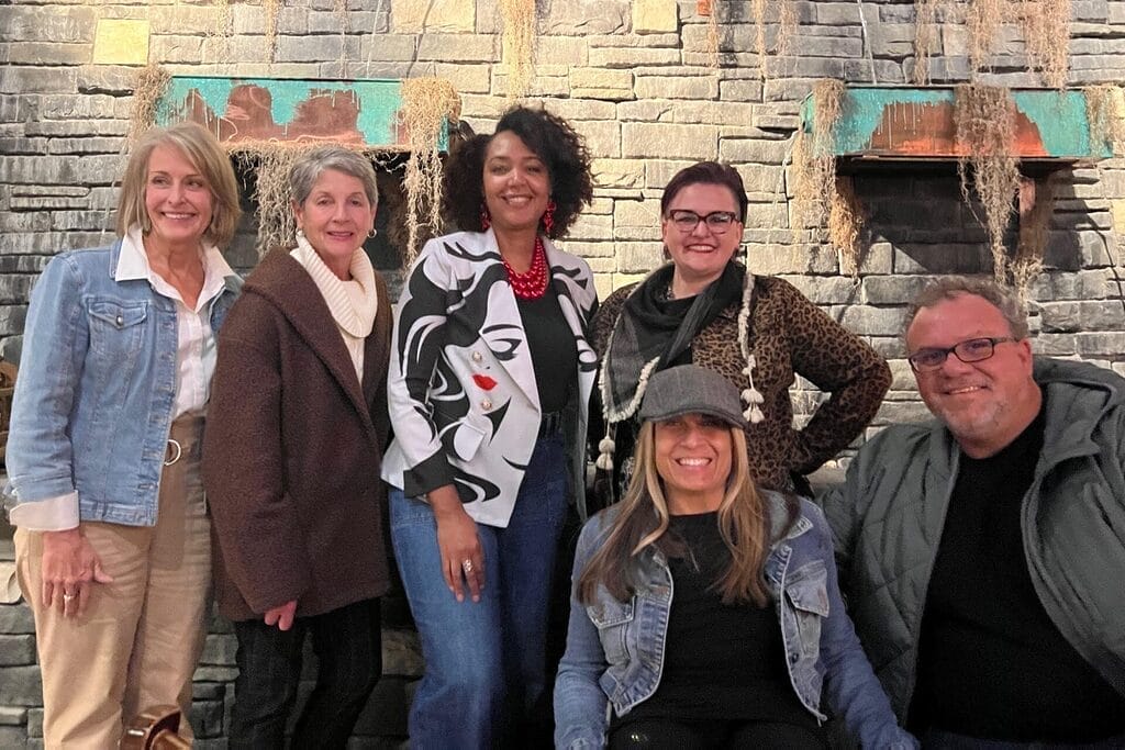 alycia and marty with members of the humana d e i team in front of a brick wall with copper planters