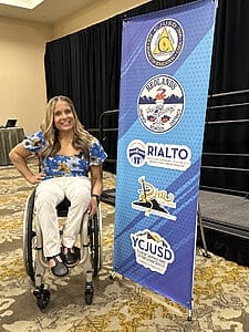 alycia next to marketing banner showing all the school districts represented at east valley selpa inclusion summit
