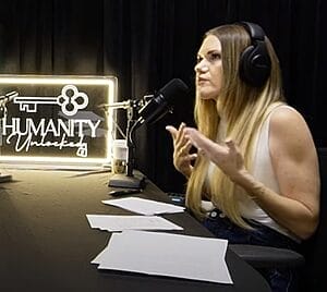 kimberly daya sitting at interview table with humanity unlocked light on table with microphone and headset
