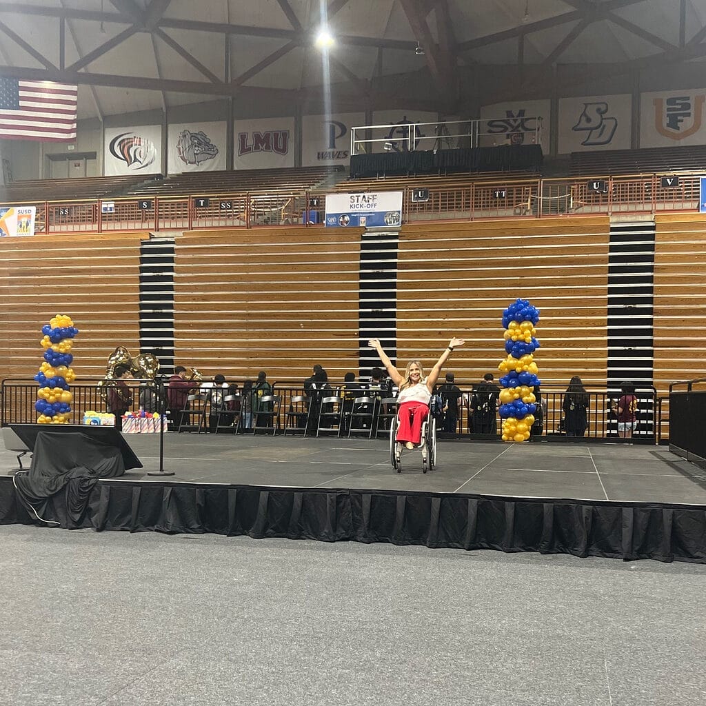 alycia on stage at s u s d kick off event with her arms in a v above her head