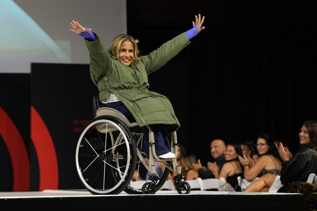 Alycia wearing a green jacket on the runway with the audience looking on