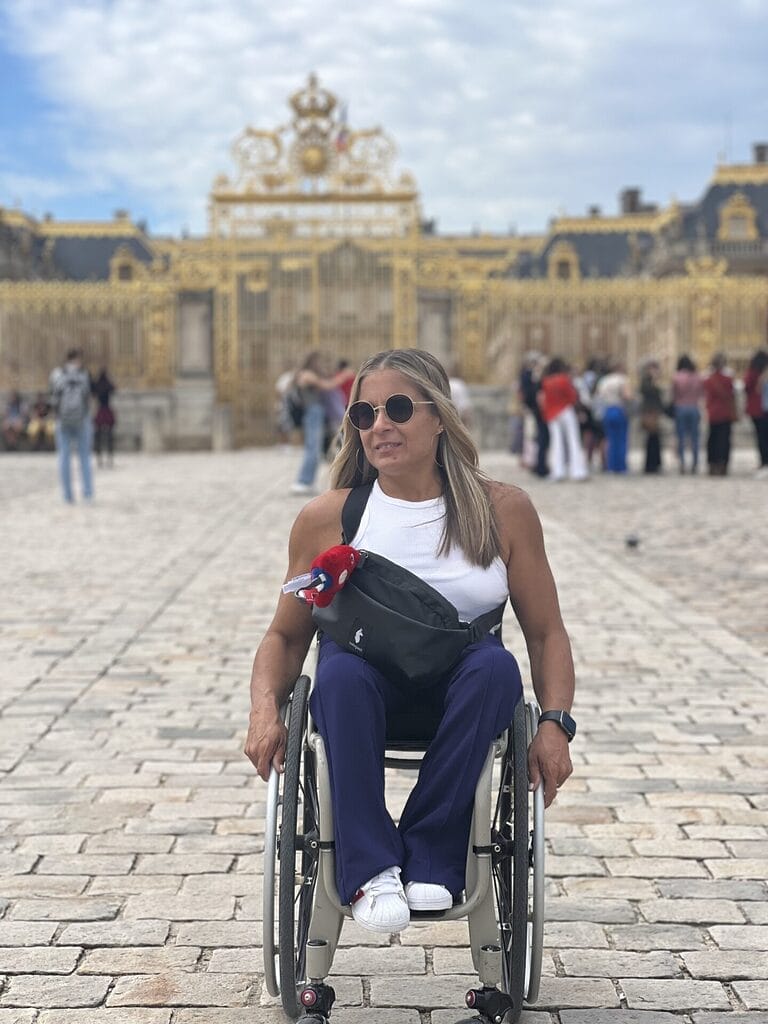 alycia sitting in her wheelchair on the cobblestones in front of the palace of versailles