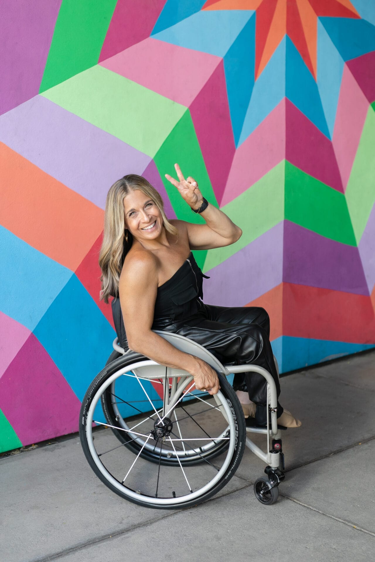 Alycia with peace sign near a rainbow mural
