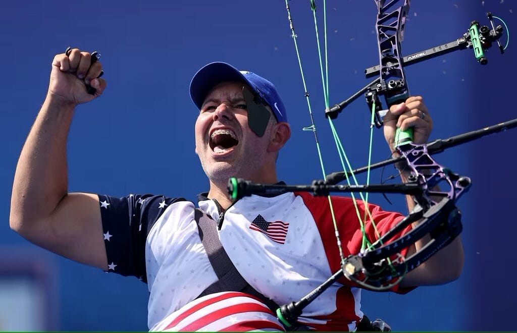 jason tabansky holding his bow and pumping his fists after winning paralympic gold
