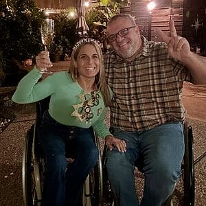 alycia and marty sitting in their wheelchairs outside toasting in the new year and giving the peace sign