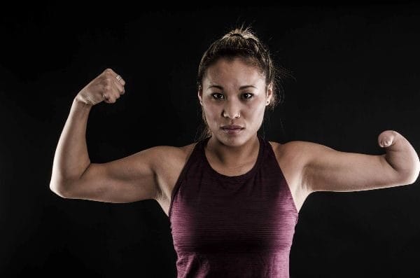 leah kaplan flexing her muscles waering workout clothes and her hair in a bun