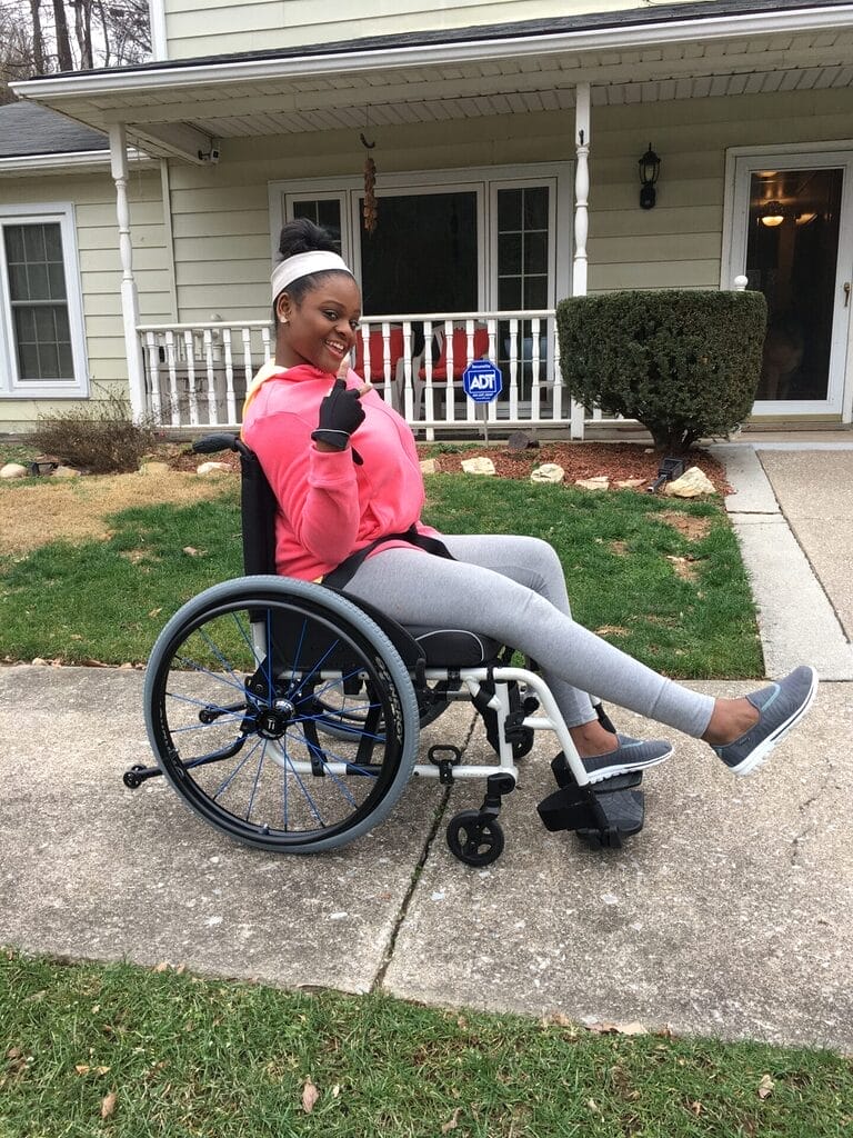 nevaeh rolling in her wheelchair in her wheelchair wearing a hot pink top