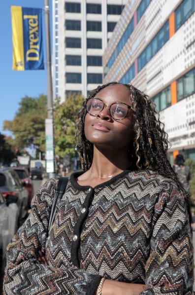 nevaeh looking up at a university of drexel banner in front of buildings