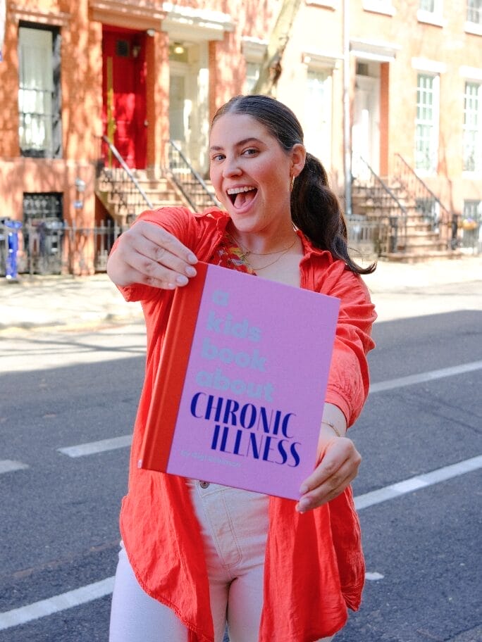 gigi robinson holding her book in front of her titled a kids book about chronic illness