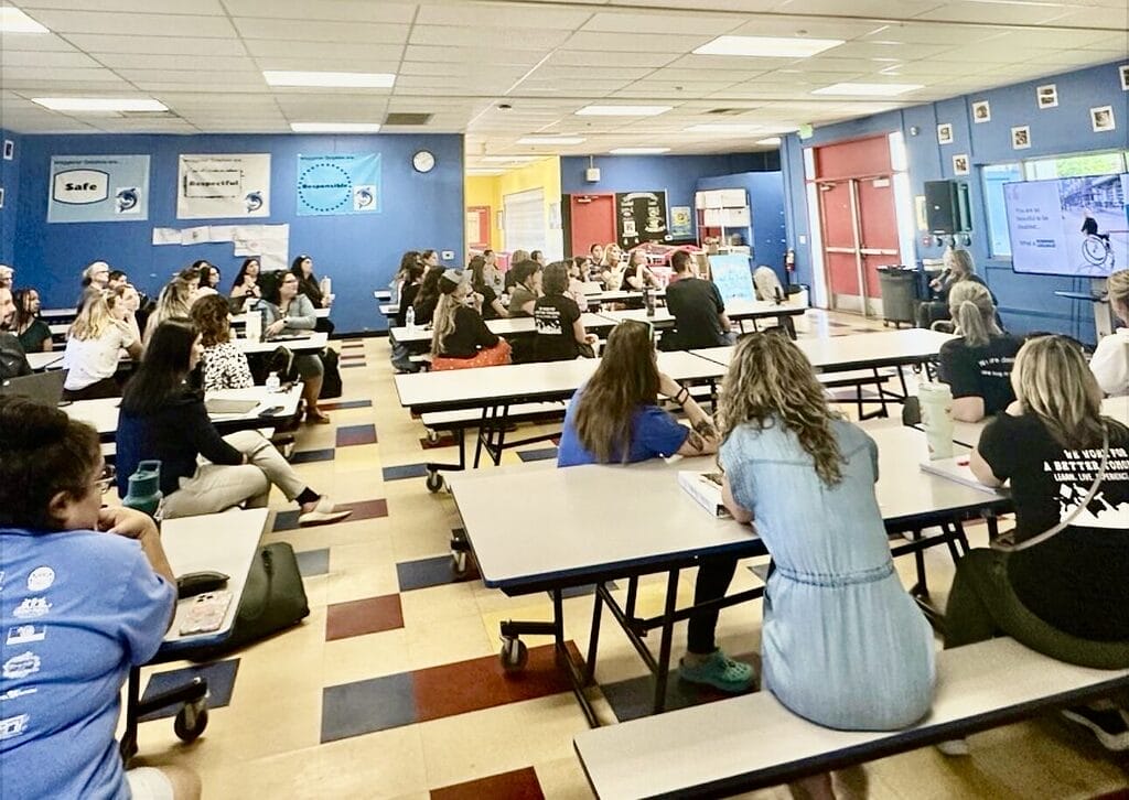 Alycia speaking to a large group of teachers
