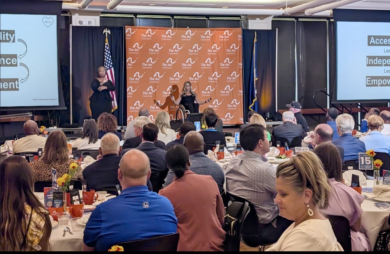 alycia on stage at the arc caddo bossier leadership luncheon in front of a large crowd