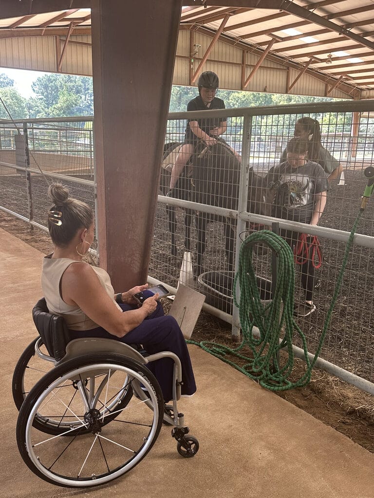 alycia watching a participant riding a horse guided by great program staff
