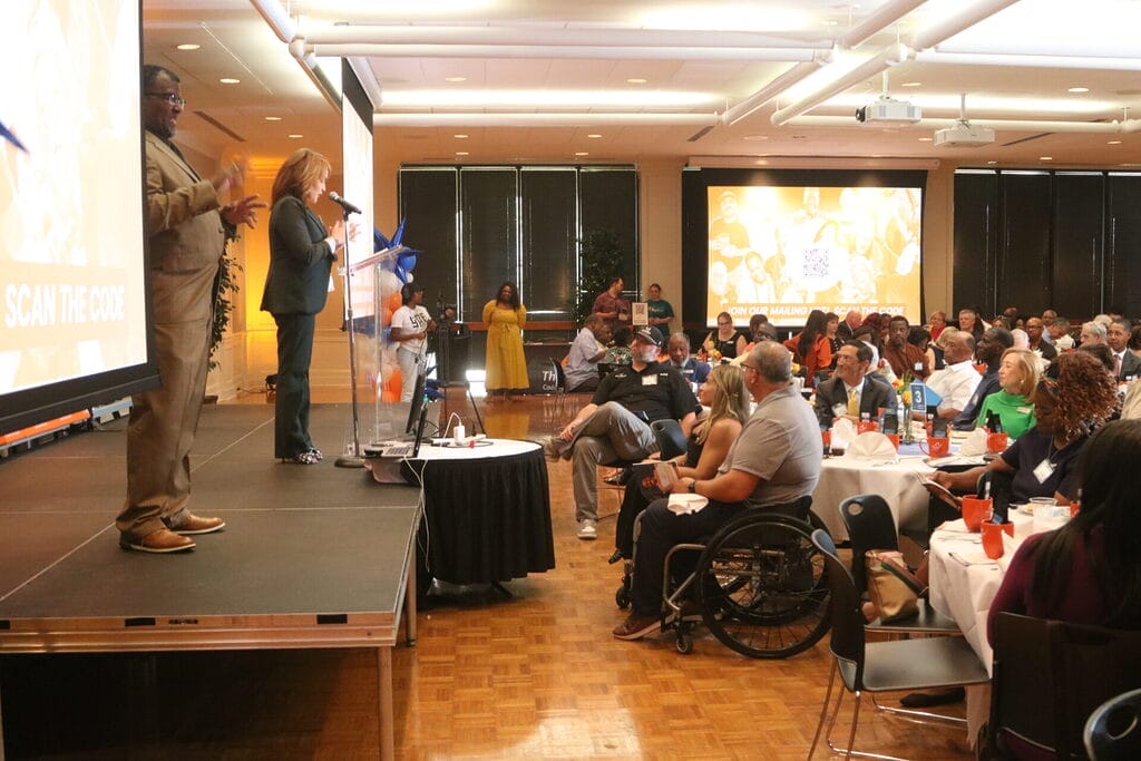 jacque jovic emmy award winning news anchor of k t a l n b c local channel six opens the event with marty and alycia sitting in the crowd in front of her