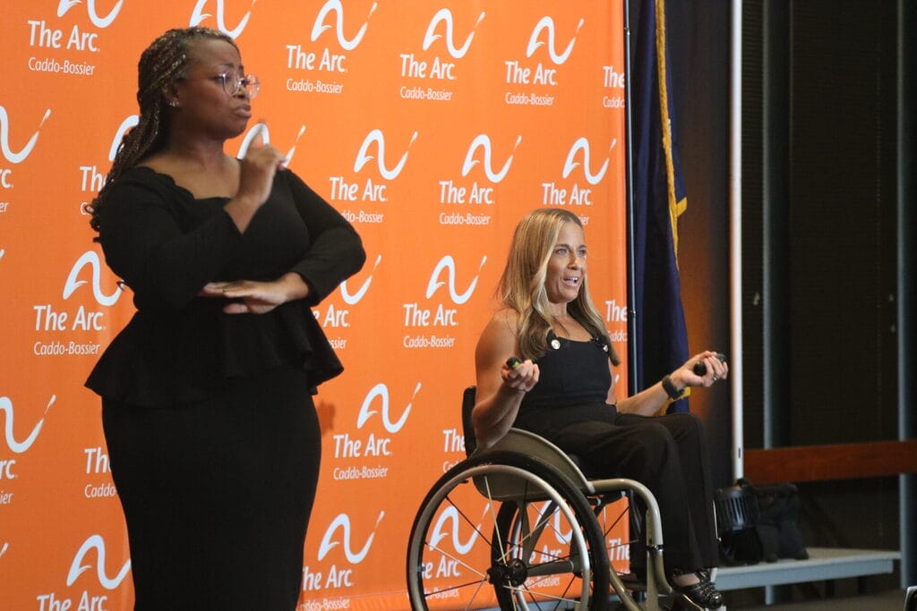 alycia on stage with a s l interpreter during speech