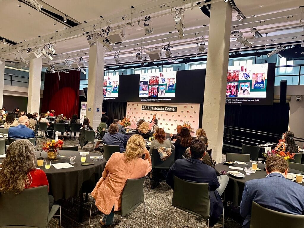 alycia in the background on stage in front of a crowded room