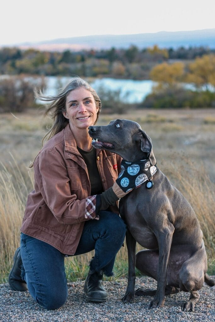 marilyn anderson in a field with a labrador wearing a bee human companion bib