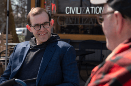 michael liner sitting with a someone outside a cafe
