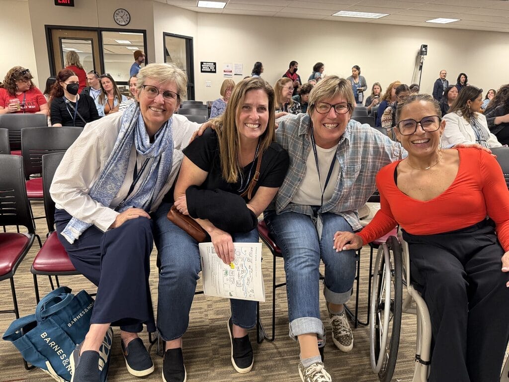 Alycia siting with a group of 3 women in the audience arm and arm