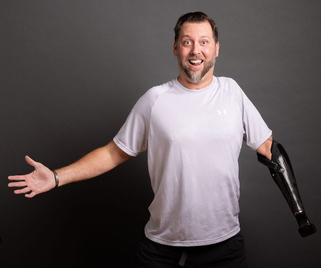 adam keys wearing a white t-shirt with his hands spread out wide smiling a big grin